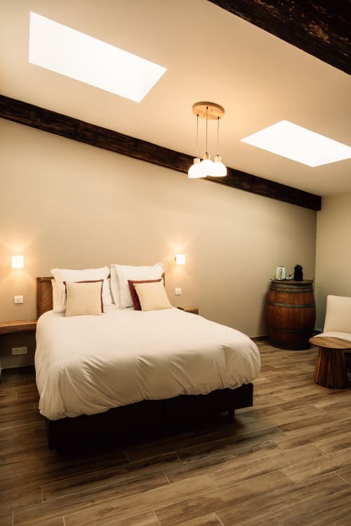 Chambre moderne au Château Alto Cormeil à Saint-Émilion avec puits de lumière, poutre apparente et mobilier en bois