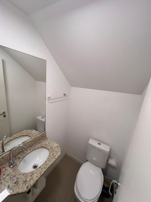 Banheiro moderno do apartamento duplex Bora Bora Hospedagens com bancada de granito, pia e louças em Joinville