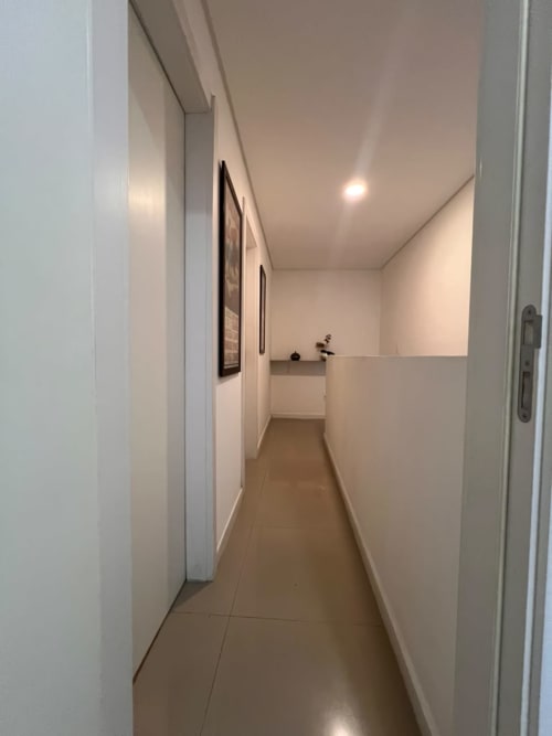 Corredor moderno em apartamento duplex BORA BORA HOSPEDAGENS, Joinville, com paredes brancas e piso em azulejos