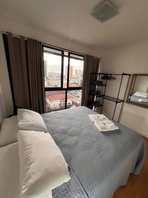 Quarto moderno em BORA BORA HOSPEDAGENS em Joinville com vista da cidade, cama de casal e skyline do bairro comercial