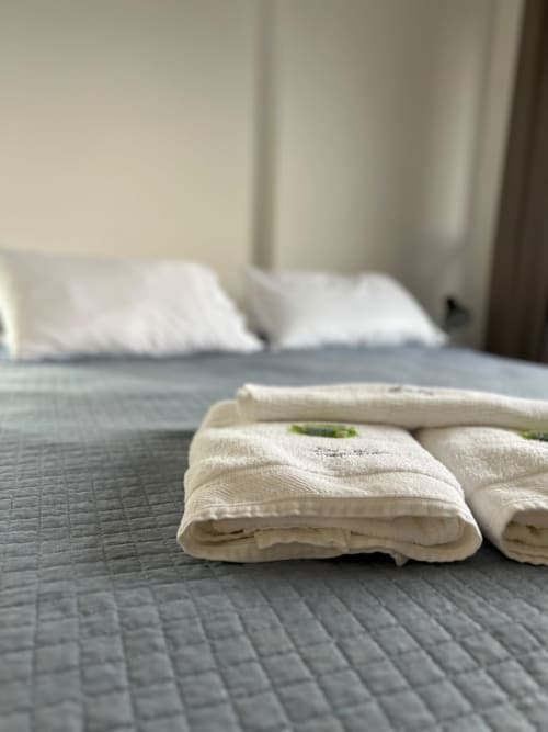 Toalhas brancas dobradas na cama do apartamento BORA BORA HOSPEDAGENS em Joinville