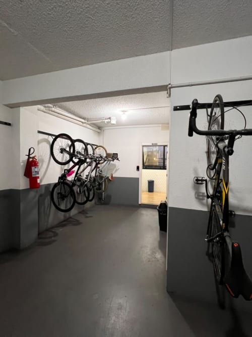 Sala moderna de armazenamento de bicicletas em apartamento de Joinville com bicicletas fixadas na parede e equipamentos de segurança