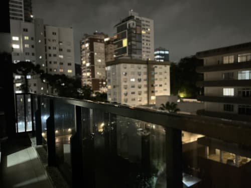 Vista noturna da cidade do balcão do apartamento duplex em BORA BORA Hospedagens em Joinville, mostrando prédios iluminados e