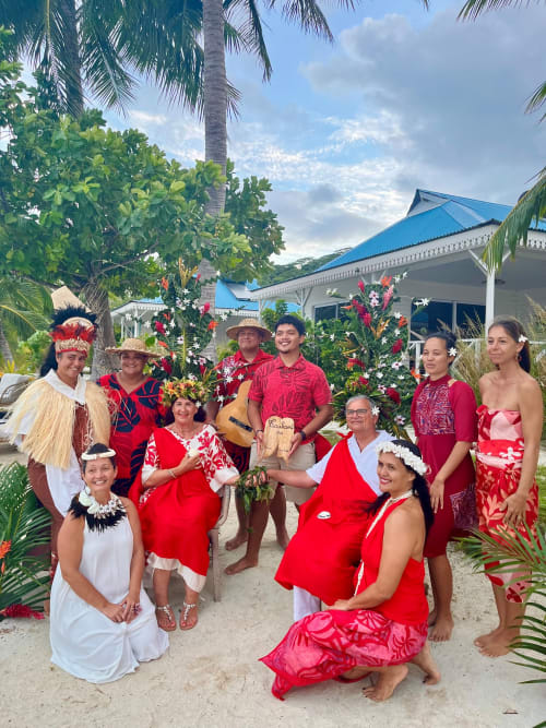 Guests in traditional Polynesian attire celebrating at Opoa Beach Hotel Uturoa with tropical decorations and palm trees