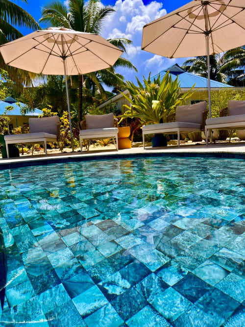 Pool des OPOA Beach Hotels mit türkisblauem Wasser, Liegestühlen, beigen Sonnenschirmen und Palmen in Uturoa