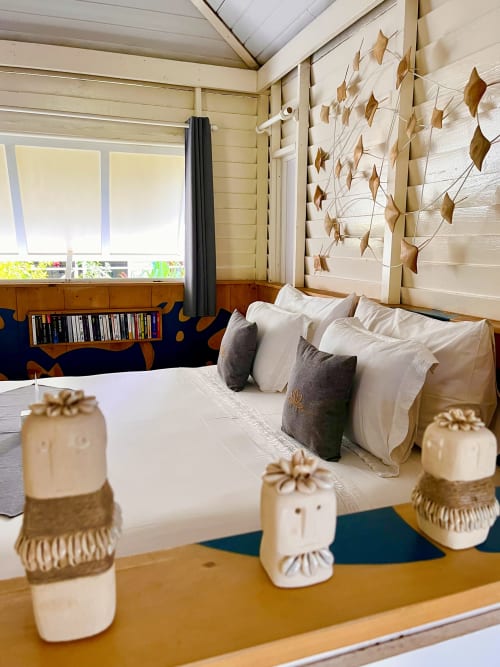 Bungalow-Gartenzimmer im OPOA Beach Hotel, Uturoa mit verziertem Bett, goldener Wandkunst und Holzdetails