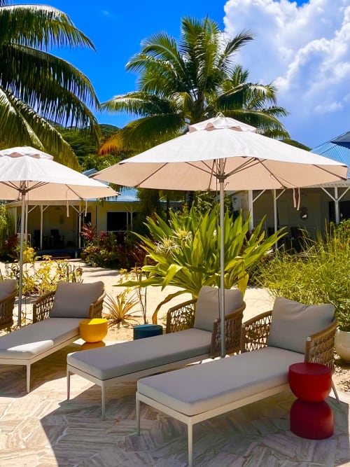 Tropical beach resort patio with loungers under umbrellas, palm trees, mountain views at OPOA BEACH HÔTEL, Uturoa