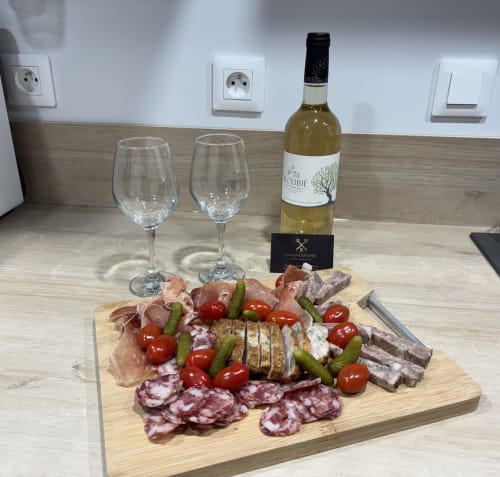 Charcuterie board with cured meats, cheese, tomatoes and pickles paired with white wine at La Conciergerie in Millau
