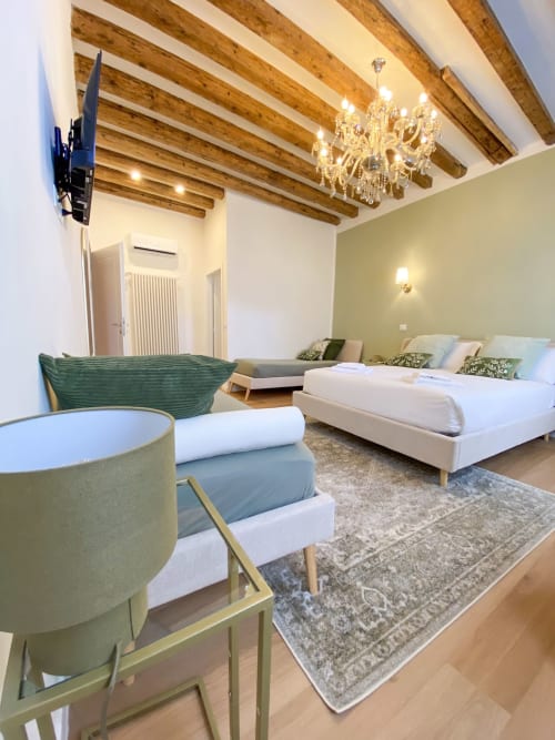 Luxurious suite in Verona with exposed beams, chandelier, twin beds, green accent wall, and elegant furnishings near Venice