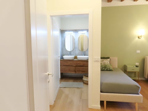 Modern bedroom suite in Verona hotel with ensuite bathroom featuring dual vessel sinks and river views