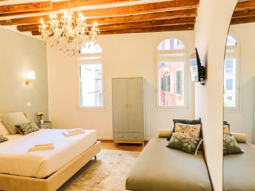 Luxury suite in Verona with wooden beams, chandelier, twin beds, canal views through arched windows, and classic furnishings