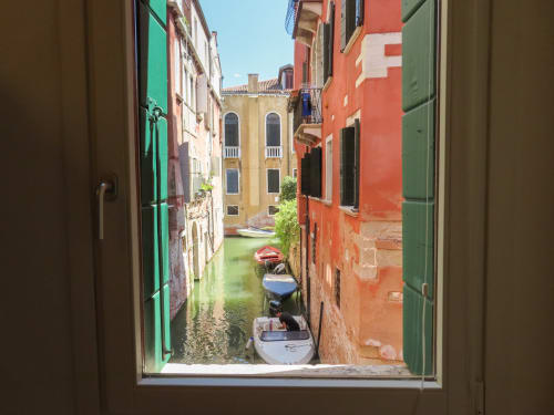 View from San Marco Luxury Suite in Venice: colorful buildings framing a narrow canal with moored boats and historic palazzo