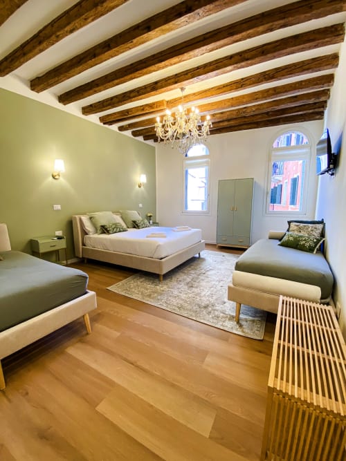 Luxurious Verona suite with exposed wooden beams, queen bed, twin bed, pale green walls, chandelier, wooden floors and canal