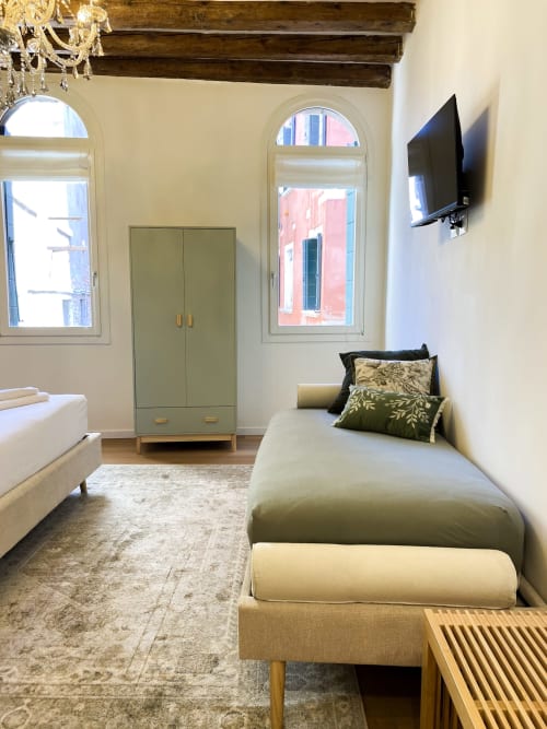 Luxury hotel suite in Verona with twin beds, wardrobe, arched windows, exposed beams, and river view