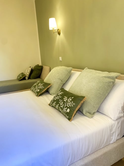 San Marco Suite Superior bedroom with white linens, green pillows, wall sconce, and olive walls in Verona