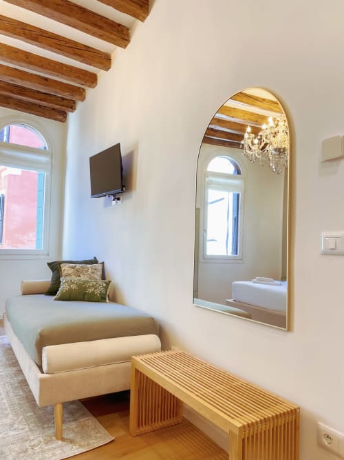 Luxury suite in Verona with wooden beams, arched mirror, flat-screen TV, upholstered daybed, and river views