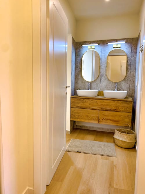 Modern bathroom with dual vessel sinks, wooden vanity, and textured tile backsplash in Verona luxury suite
