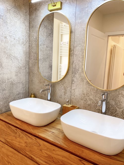 Luxurious double sink bathroom in San Marco Suite, Verona. White vessel sinks, brass-framed mirrors, patterned wallpaper,