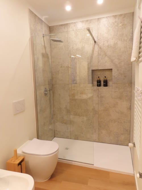 Modern bathroom with walk-in shower, white toilet, wooden floor, and built-in storage at luxury Verona suite