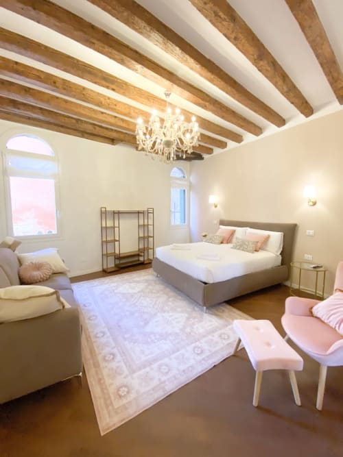 Luxury bedroom suite in Verona with exposed wooden beams, crystal chandelier, king bed, and river views