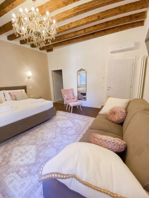 Luxury suite in Verona with exposed wooden beams, crystal chandelier, bed, sofa, and river view