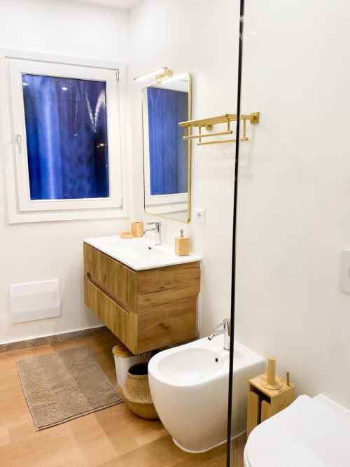 Modern bathroom in Verona luxury suite with wooden vanity, gold mirror and fixtures, white bidet, and wooden flooring