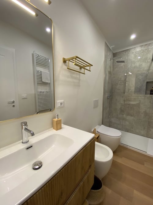 Modern bathroom in Verona luxury suite with marble shower, vanity sink, heated towel rack, and brass fixtures