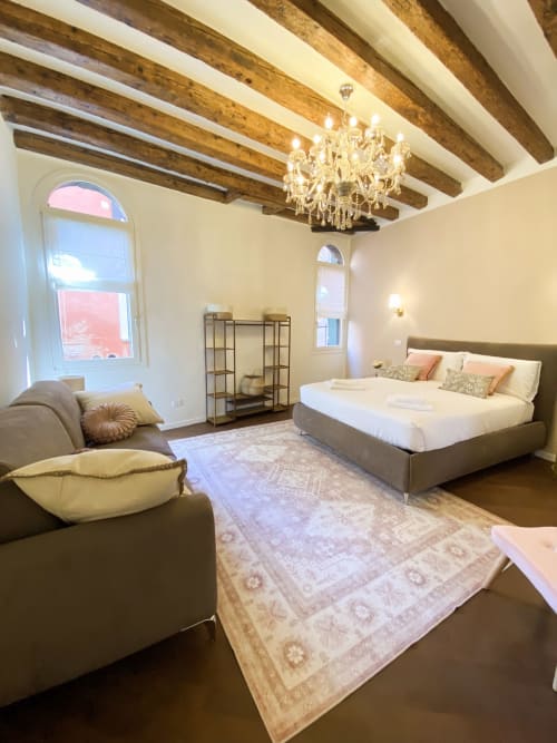 Luxurious Suite Superior in Verona with exposed wooden beams, crystal chandelier, queen bed, seating area, and river view