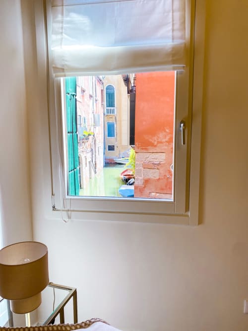Window view of Venice canal with colorful buildings and boats from luxury suite in Verona hotel