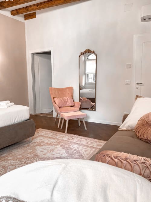 Elegant suite bedroom in Verona with pink velvet chair, wooden beams, mirror, and parquet flooring at luxury B&B San Marco