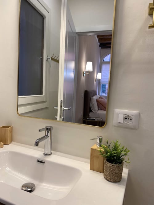 Modern bathroom sink with mirror in Verona luxury hotel suite, featuring white basin, chrome faucet, and river view