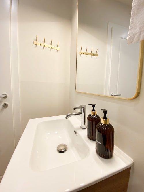 Modern bathroom sink with chrome faucet, dark toiletries, and brass hooks at luxury San Marco suite in Verona, Italy
