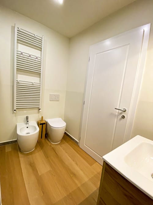 Modern bathroom in San Marco Luxury Suite, Verona with white bidet, toilet, pedestal sink, heated towel rack, and wooden