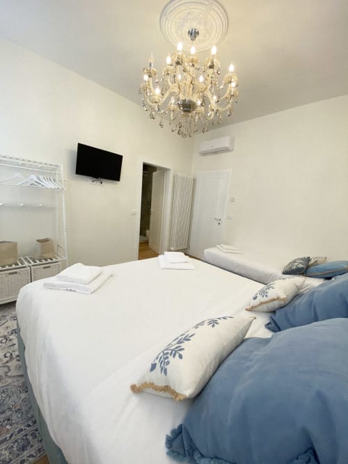 Elegant bedroom at San Marco Luxury Suites in Verona with dual beds, crystal chandelier, flat-screen TV, and modern amenities