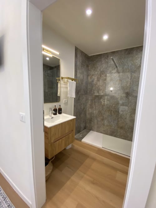 Modern bathroom in San Marco Luxury Suite, Verona with wooden vanity, dark tile shower, and illuminated mirror