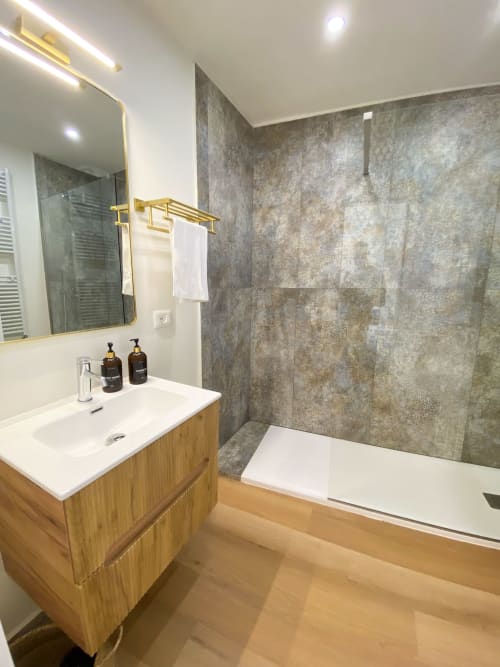 Modern bathroom in San Marco Luxury Suites, Verona with wooden vanity, gray tile shower, and gold accents