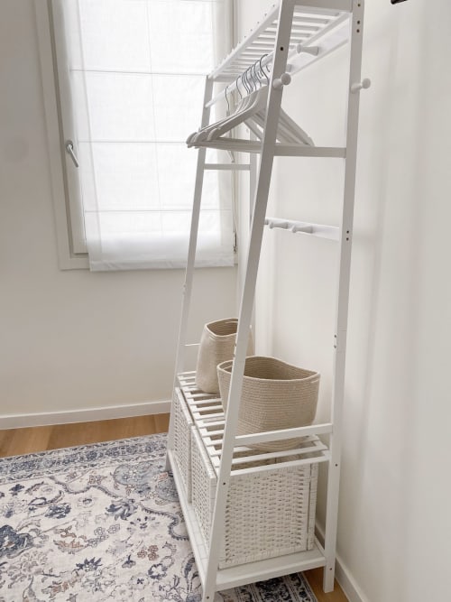 White clothing rack with woven storage baskets in bright bedroom of San Marco Luxury Suites, Verona