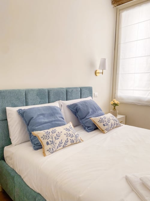 Elegantly styled bedroom with blue upholstered headboard, white bedding, and decorative pillows at San Marco Luxury Suites,