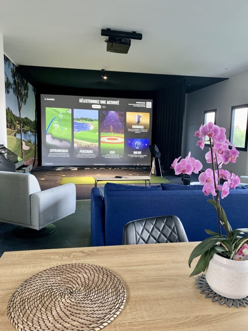 Salle de cinéma maison moderne à STAYnGOLF à Cagnes-sur-Mer avec simulateur de golf Trackman, canapé bleu, orchidées roses et activités