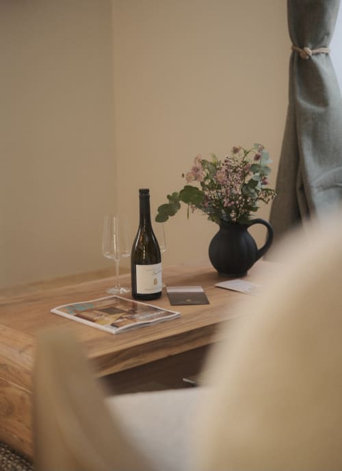 Elegant apartment setting at Moulin Renaudiots in Nolay with wine bottle, glasses, and fresh flowers on wooden table