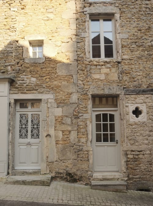 Historic stone facade of Moulin Renaudiots apartment in Nolay, France with white doors and windows