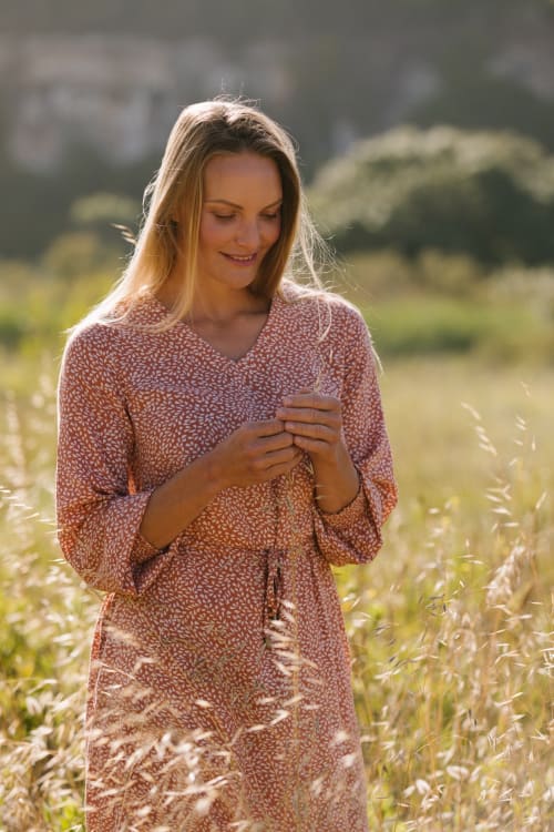 Mulher com vestido estampado em tons de ferrugem em campo de trigo dourado, Coastline Rentals Portugal