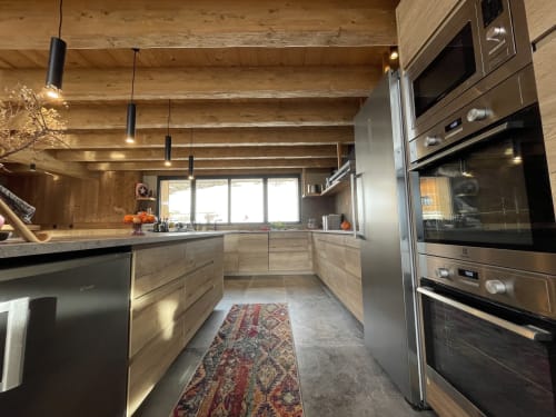 Cuisine moderne avec électroménagers en acier inoxydable, meubles en bois et luminaires suspendus au Chalet Monts d'Argent aux Chalets