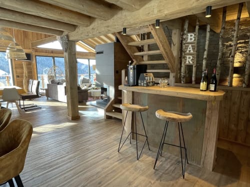 Bar de luxe du chalet avec tabourets en bois, bouteilles de vin et vue sur les montagnes aux Chalets d'Aline, La Plagne