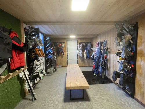 Salle de rangement de l'équipement à la villa Les Chalets d'Aline à La Plagne, avec skis, chaussures et équipement hivernal organisés sur les murs