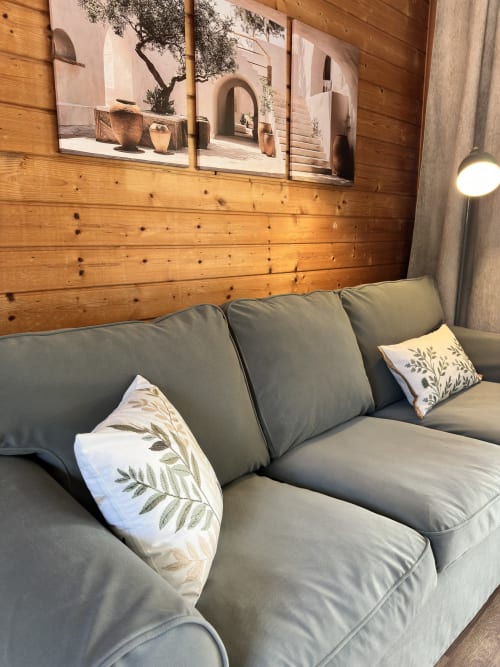 Sofá estofado cinzento com almofadas de padrão folhado em bungalow de madeira em Monte da Tojeirinha, Montargil, Portugal