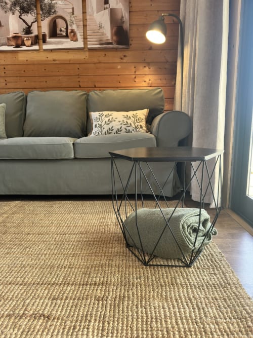 Sala de estar moderna com sofá verde sálvia, mesa lateral geométrica e paredes de madeira natural no bungalow Monte da Tojeirinha em