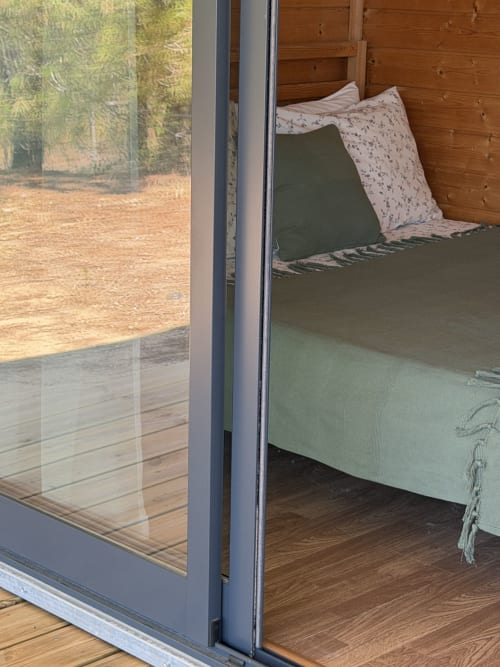 Vista do quarto de bungalow com 2 quartos na Monte da Tojeirinha, com vista para o lago, terraço em madeira e roupa de cama verde