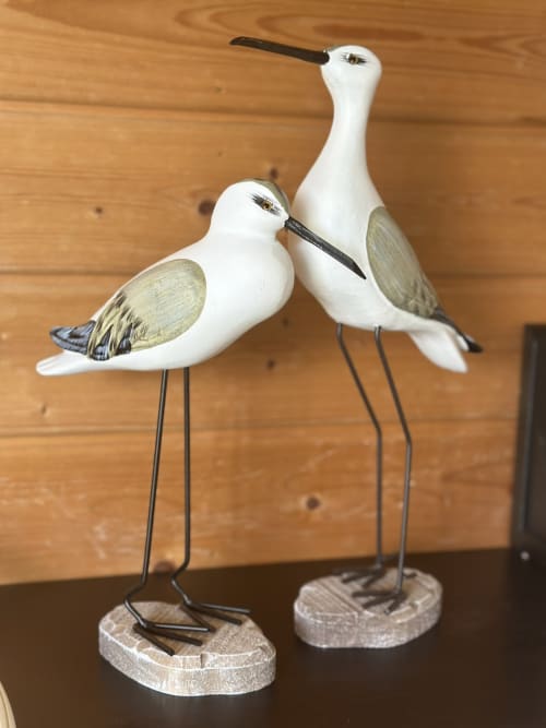 Par de pássaros decorativos brancos com asas douradas em bases de madeira na pousada Monte da Tojeiranha