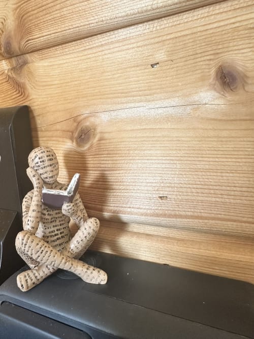 Boneca de tecido caprichosa lendo um livro em prateleira de madeira no bungalow Monte da Tojeirinha em Montargil, Portugal